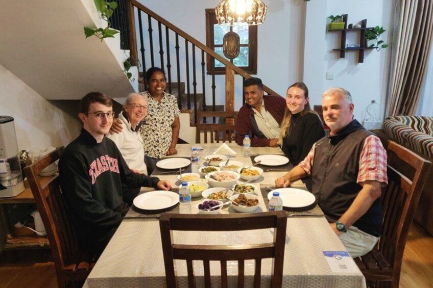 A group of people seated around a dining table with various dishes. 2