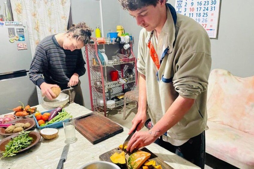 Two people preparing food in a kitchen with vegetables, a cutting board, and a calendar on the wall. 4