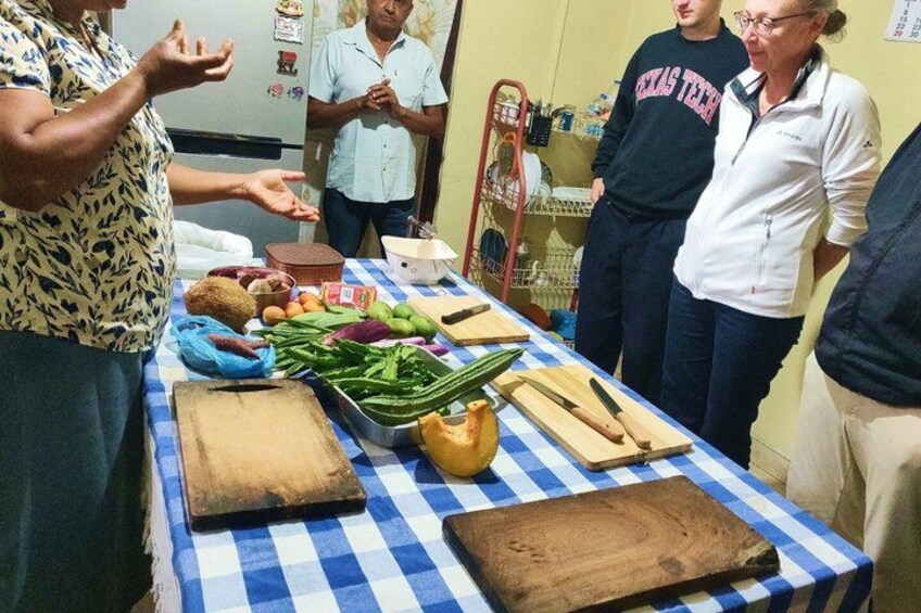 A group of people around a table with vegetables and kitchen tools. 5