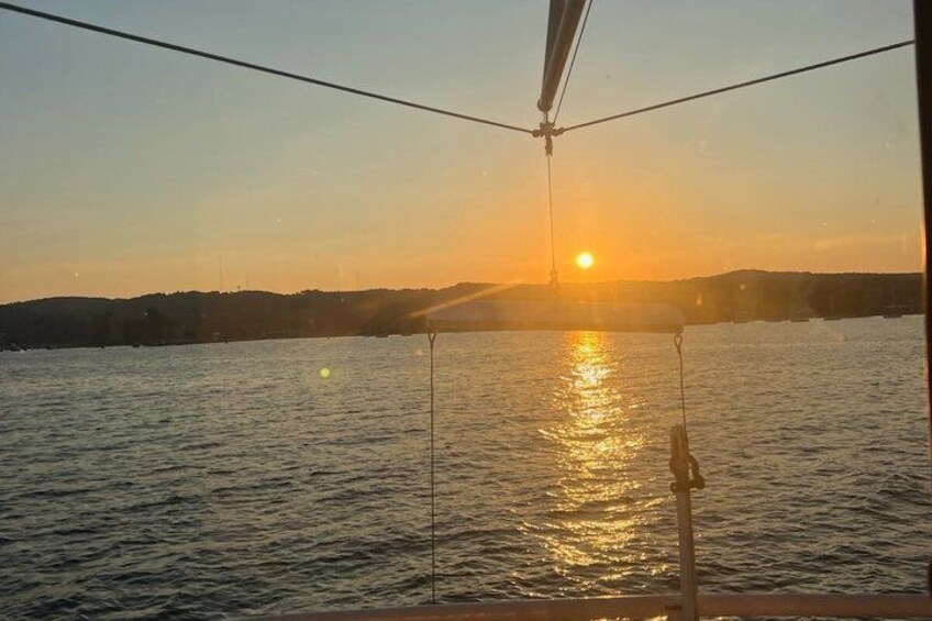A sunset over a body of water with a boat and a distant shoreline. 4