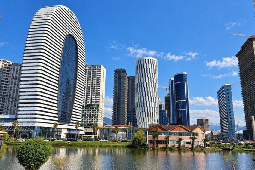 A cityscape with modern skyscrapers, a body of water, and a clear blue sky. 4