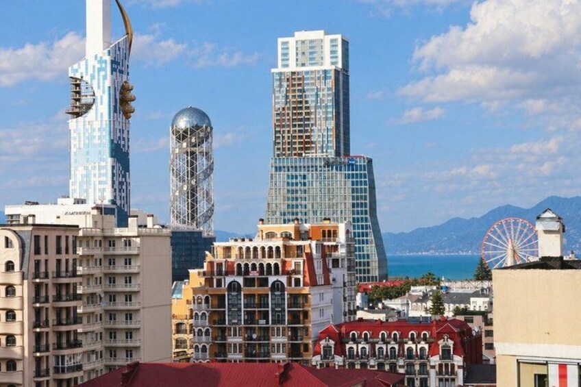 A cityscape with modern skyscrapers, a historic building, and a red-roofed structure. 2