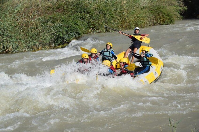 A group of people in a yellow raft navigating a river. 2