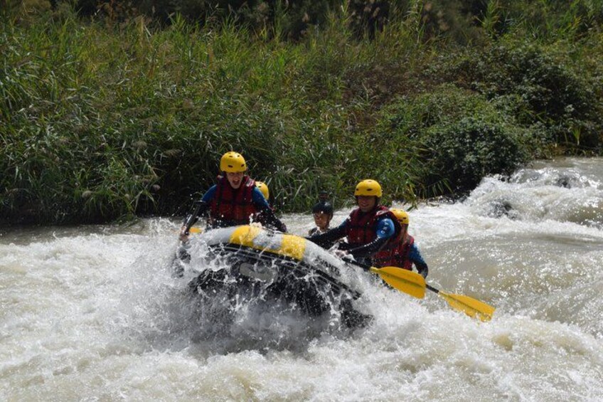 Two people in a yellow raft navigating a river with rapids. 4