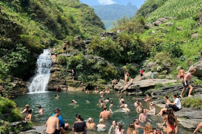 A waterfall, rocky terrain, and people swimming in a natural pool. 5