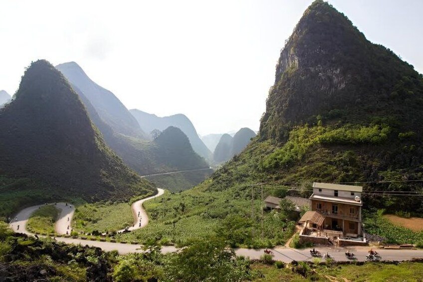 A winding road through a mountainous landscape with a building on the right. 2