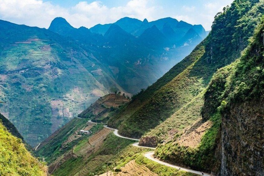 A winding mountain road surrounded by lush green hills and distant mountain peaks. 3