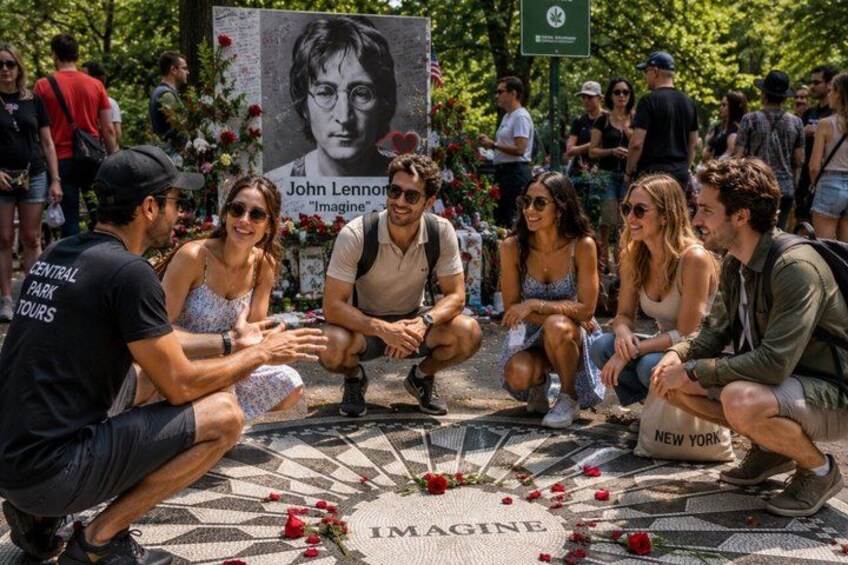 A group of people sitting on patterned tiles with a 'Imagine' sign and a 'New York' bag. 3