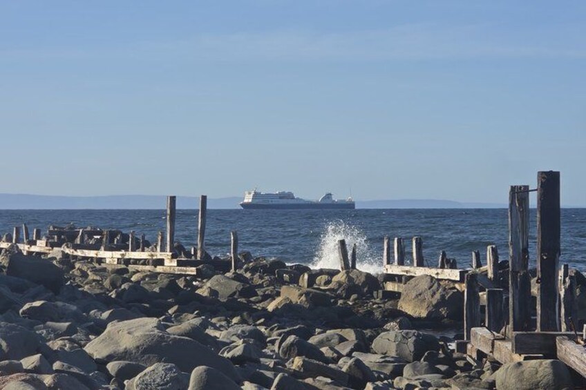 A rocky pier with a ship in the distance. 4
