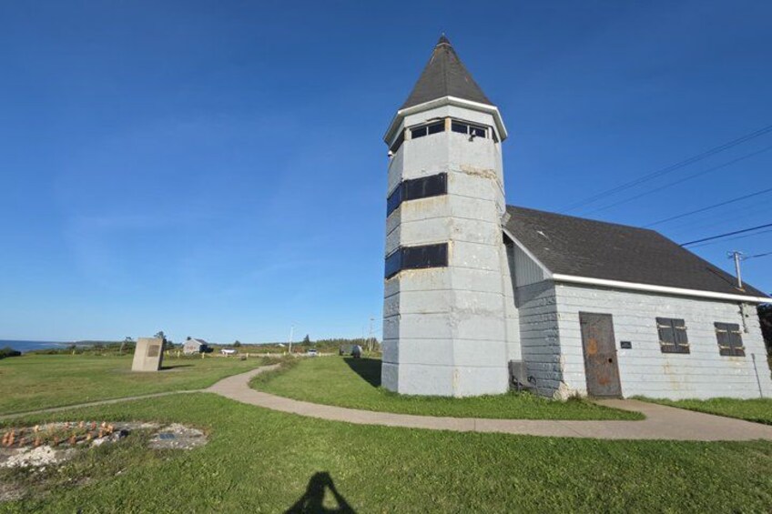 A white church with a bell tower, a grassy field, and a clear blue sky. 5