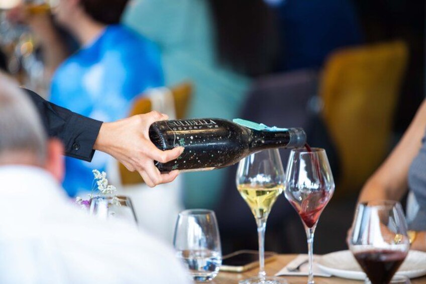 A person pouring a drink from a bottle into a glass. 5