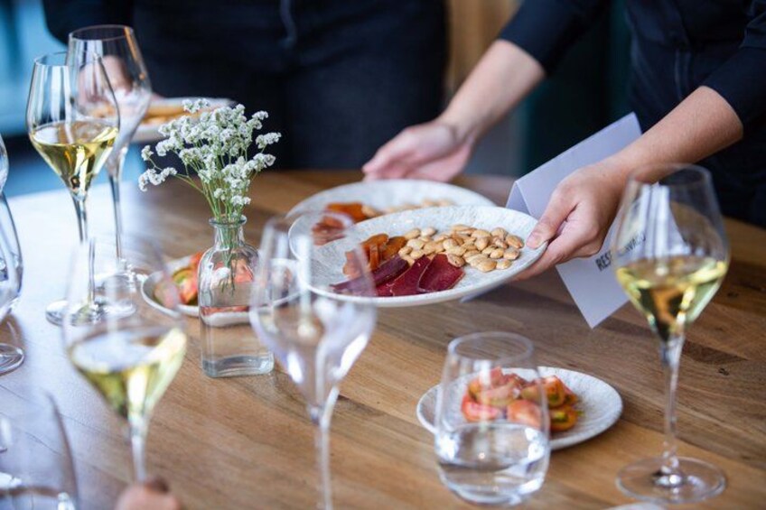 A dining table with plates of food, wine glasses, and a small vase with flowers. 1