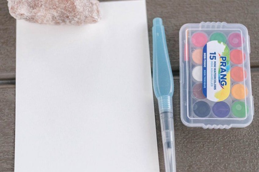 A white paper, a blue pen, and a container of PRANG watercolor paints. 2