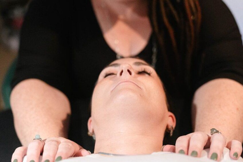 A person lying down with hands resting on a surface, and another person standing behind them. 5