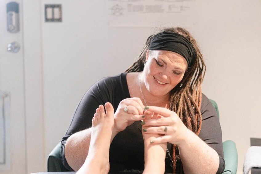 A person sitting at a table with their feet being examined by another individual. 2