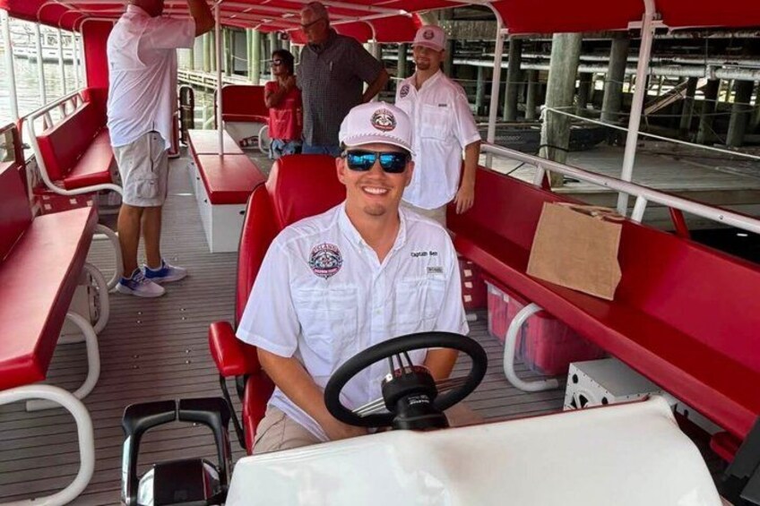 A boat with red benches and a person steering. 2