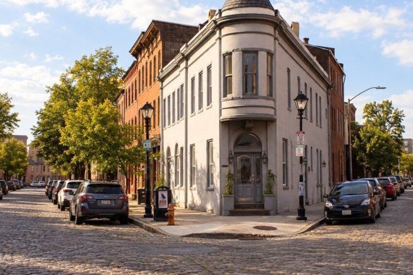 A cobblestone street lined with parked cars and historic buildings. 4