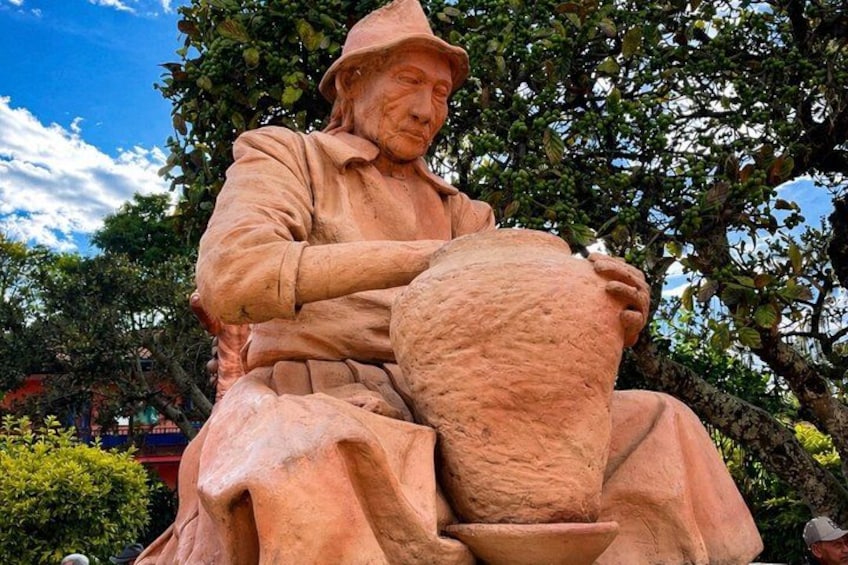 A stone statue of a seated figure with a pot. 2