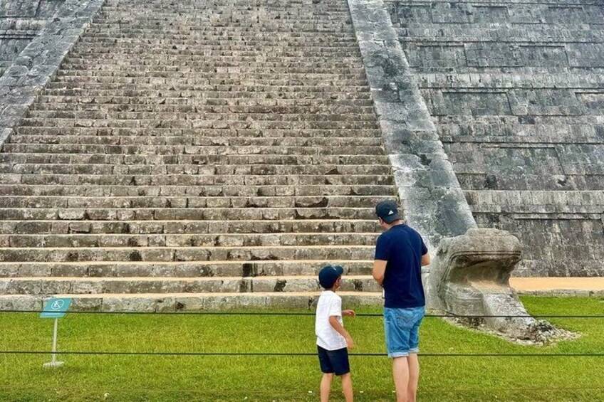 A large stone staircase leading up to a pyramid, with a person and a child standing at the bottom. 3