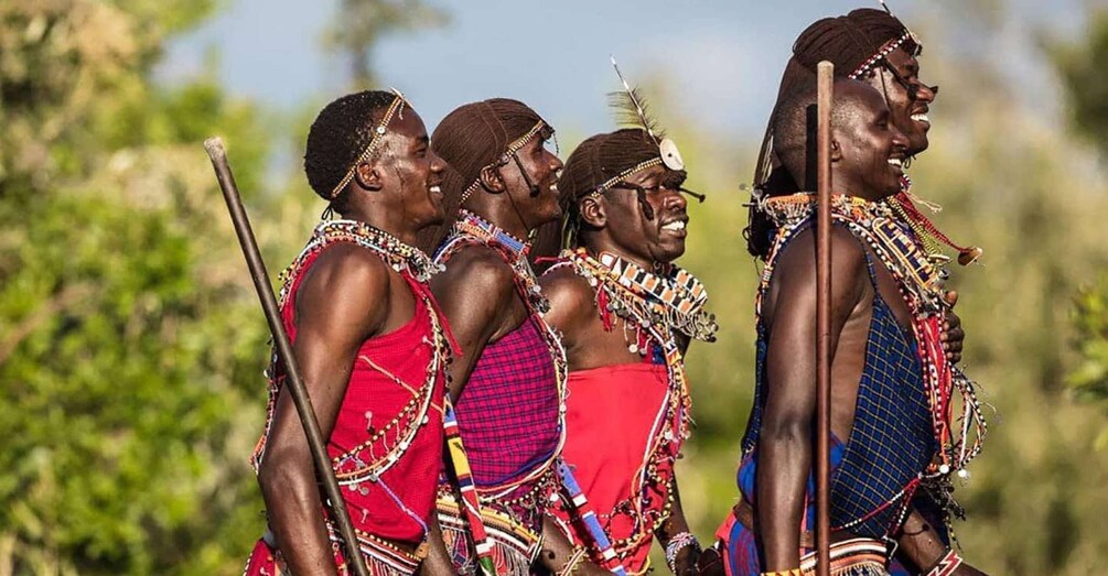A group of people in traditional attire with spears, standing outdoors. 1