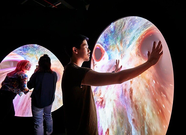 Une personne interagissant avec un grand écran numérique sphérique dont le design évoque l’univers. 3