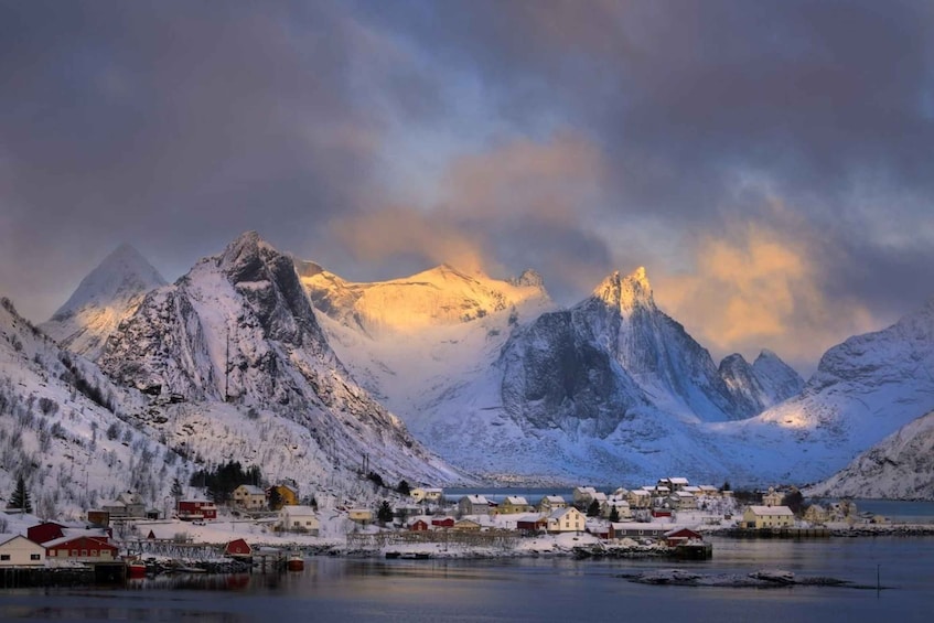 A coastal village with snow-covered mountains and a calm sea. 2