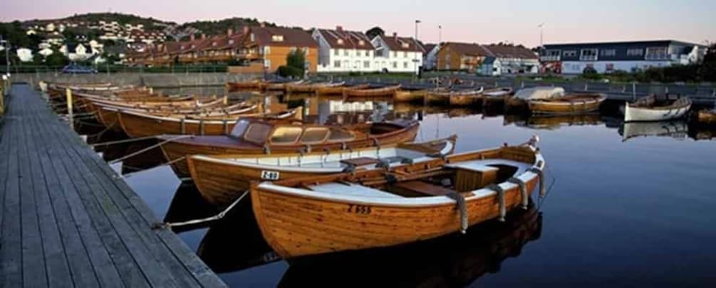 A marina with wooden boats docked along a wooden pier, surrounded by houses and buildings. 3