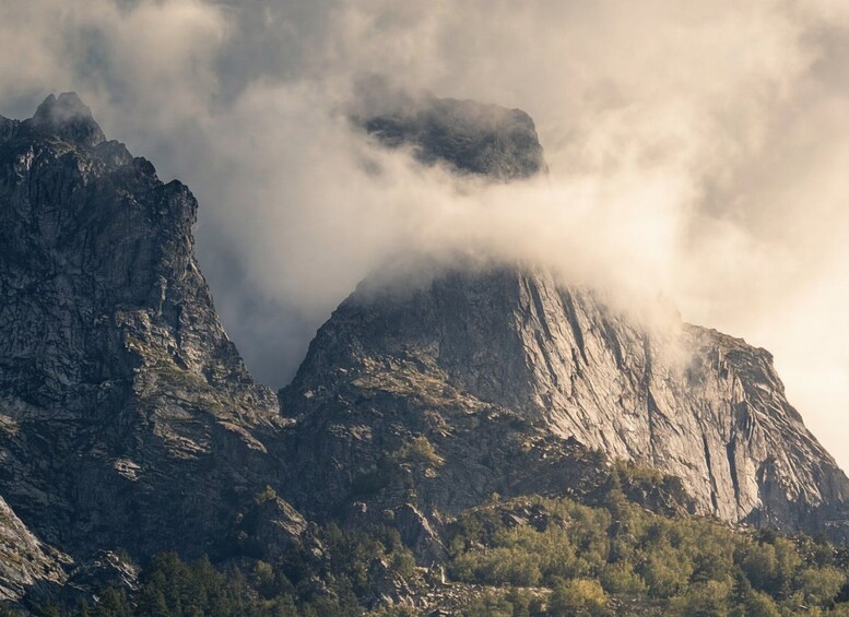 Una cordillera escarpada con acantilados pronunciados y una base boscosa, parcialmente cubierta por nubes. 2