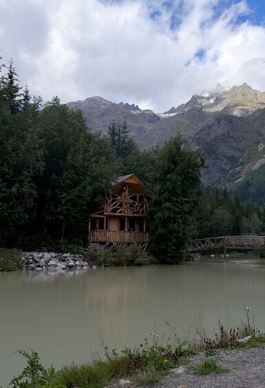 Una cabaña de madera junto a un lago, con montañas al fondo. 3
