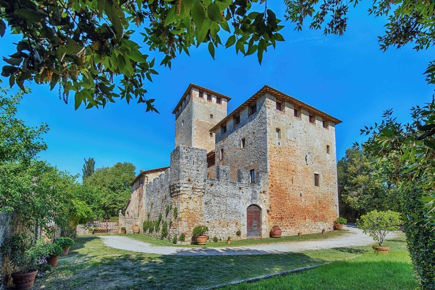 A historic stone building with a tower, surrounded by a well-maintained garden and trees. 5