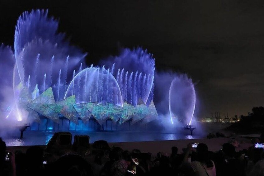 A nighttime water fountain show with illuminated water jets and a geometric light sculpture. 4