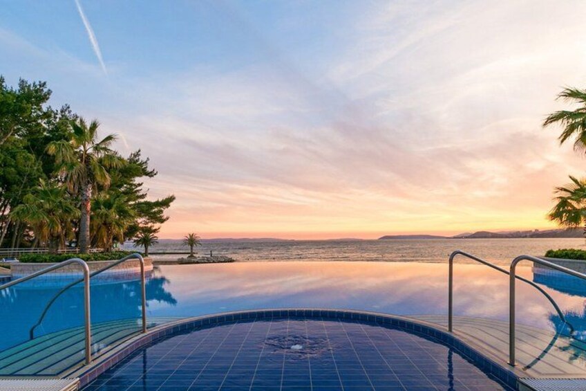 A swimming pool with a view of the ocean at sunset. 4