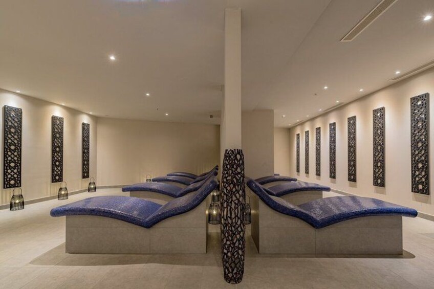 A modern spa with massage tables, decorative wall panels, and a central column. 5