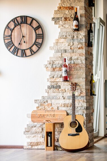 Un mur en bois orné d’une horloge, d’une guitare et de bouteilles de vin. 3
