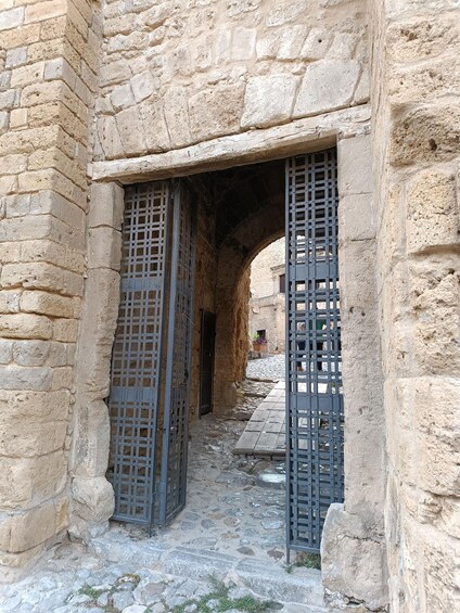 An ancient stone building with a narrow passageway and metal gates. 4