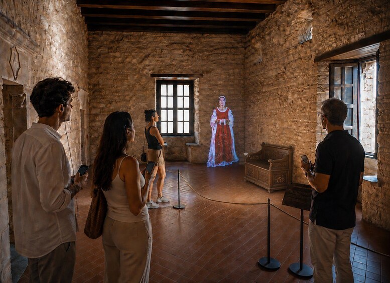 A historical building interior with stone walls, a wooden floor, and a person in period costume. 1