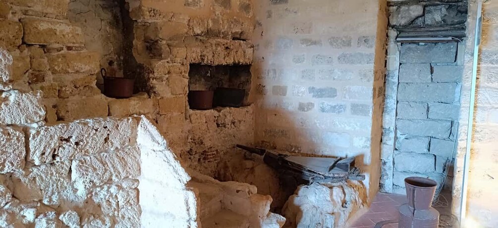 A rustic stone interior with brick walls, a hearth, and a chimney. 2