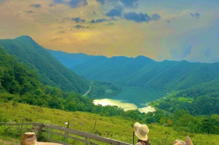 A mountainous landscape with a lake and a wooden fence. 2