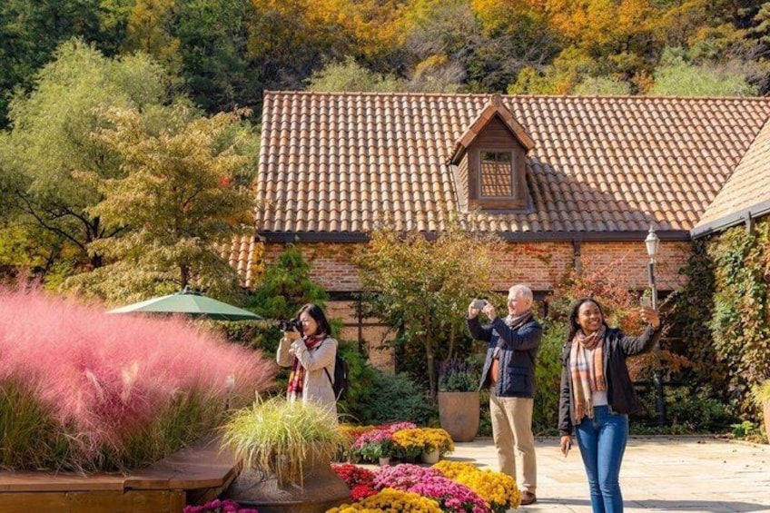 A house with a tiled roof, surrounded by flowering plants and trees. 1
