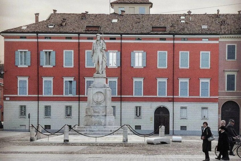 A red and white building with a statue in front. 2