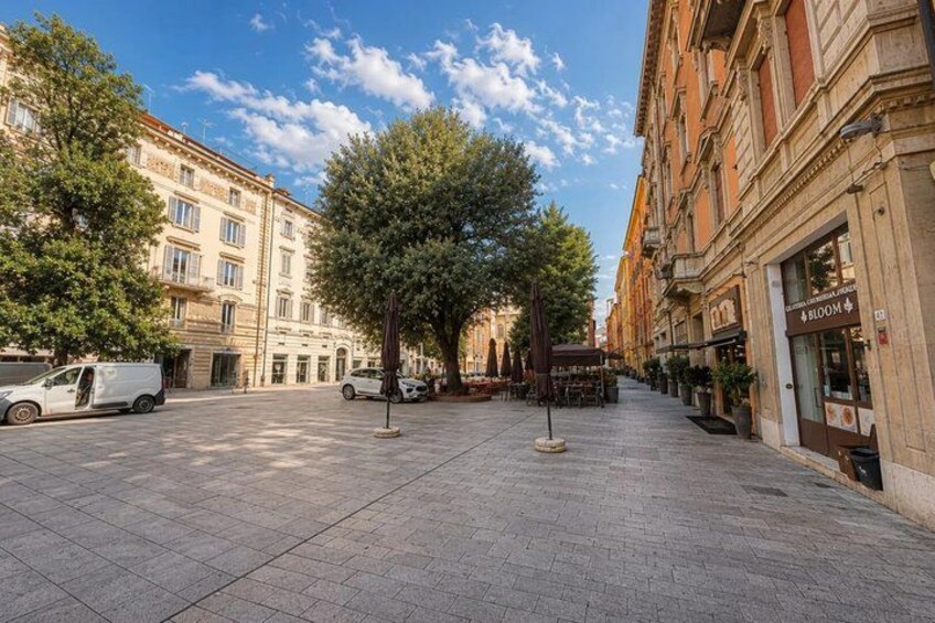 A paved square with trees, buildings, and a white van. 3