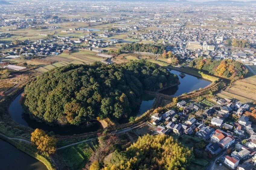 An aerial view of a town with a large forested area, a river, and residential buildings. 2