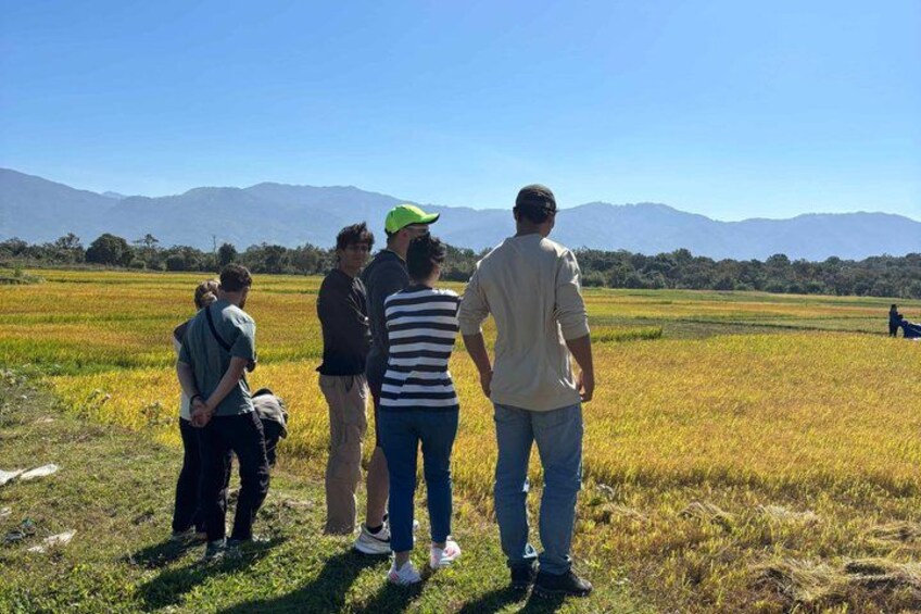 A group of people standing in a field with mountains in the background. 5