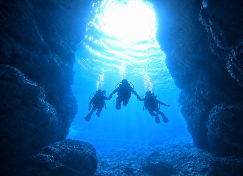 Two scuba divers in a blue underwater cave with sunlight filtering through. 2