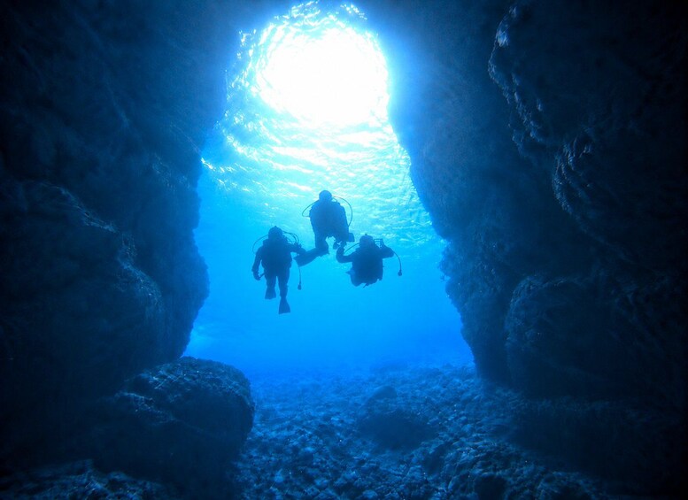 Dos buzos en una cueva azul sumergida, con una luz brillante al final. 3
