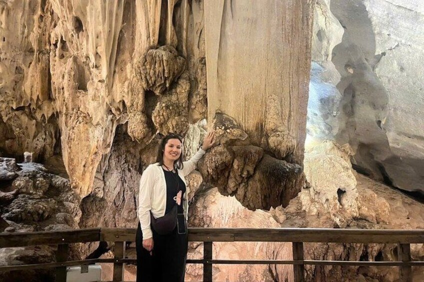 A person standing in a cave with stalactites and stalagmites. 5