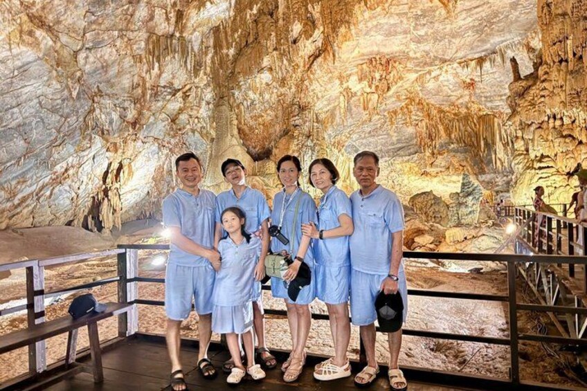 Un grupo de personas en una cueva con estalactitas y un pasillo de madera. 4