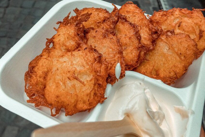 A tray of crispy potato pancakes with a dipping sauce. 4
