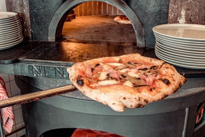 A pizza being cooked in a wood-fired oven. 5