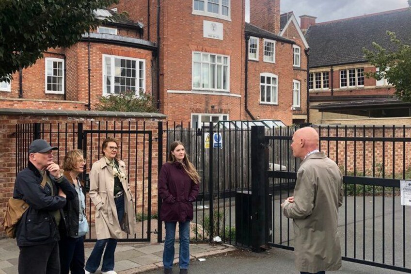 A group of people standing in front of a gated entrance with a brick building in the background. 4